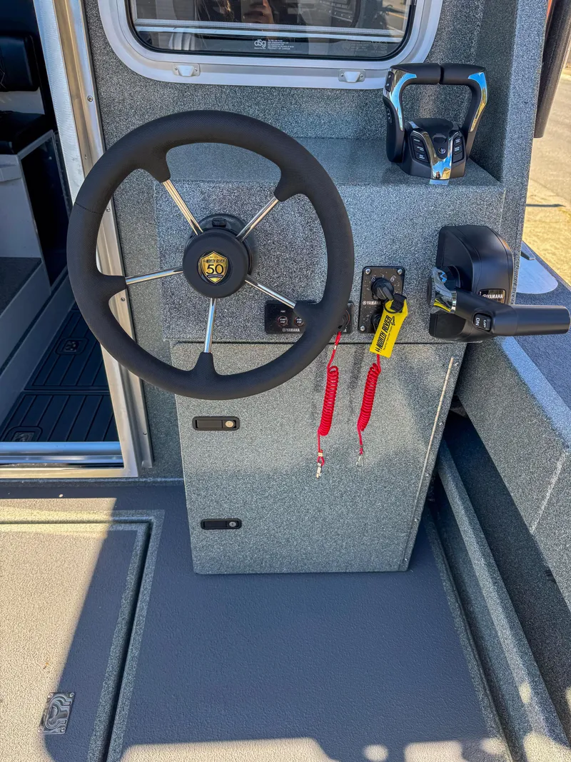 Slide: The Image of 2024 North River Seahawk OS 2700SXL boat steering console with controls and safety lanyards. - 14