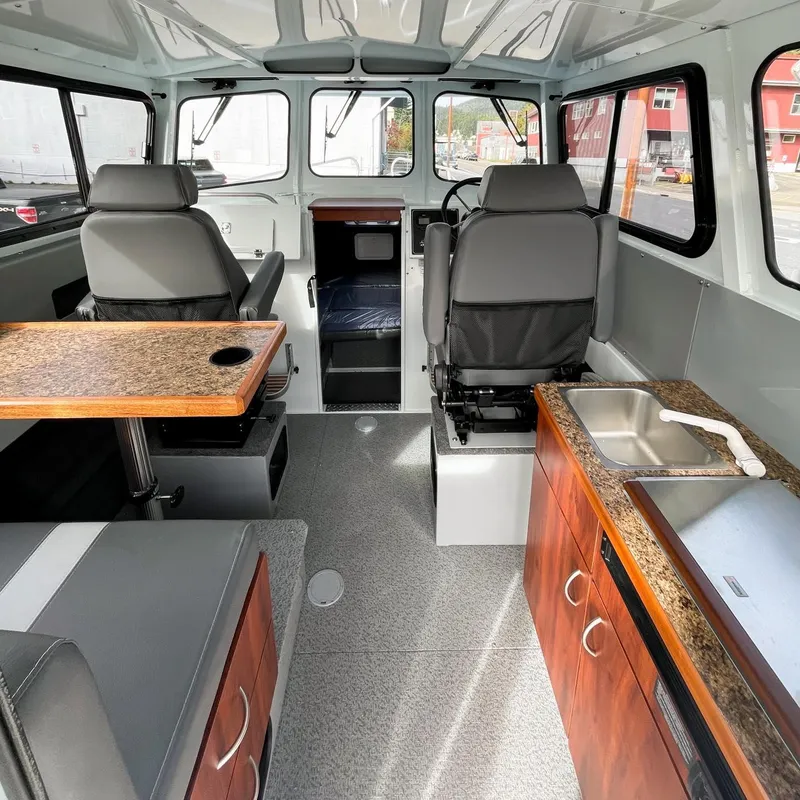 Slide: The Image of Interior of 2024 Hewescraft 240 Pacific Cruiser with seating, table, and kitchenette. - 3