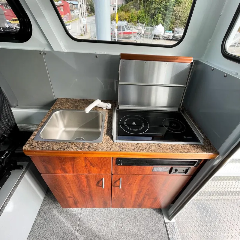 Slide: The Image of Compact kitchen area in 2024 Hewescraft 240 Pacific Cruiser boat with sink and stove. - 7
