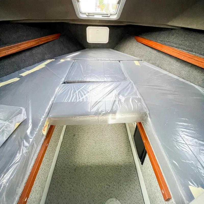 Slide: The Image of Interior cabin of 2024 Hewescraft 240 Pacific Cruiser boat with plastic-covered bedding. - 8