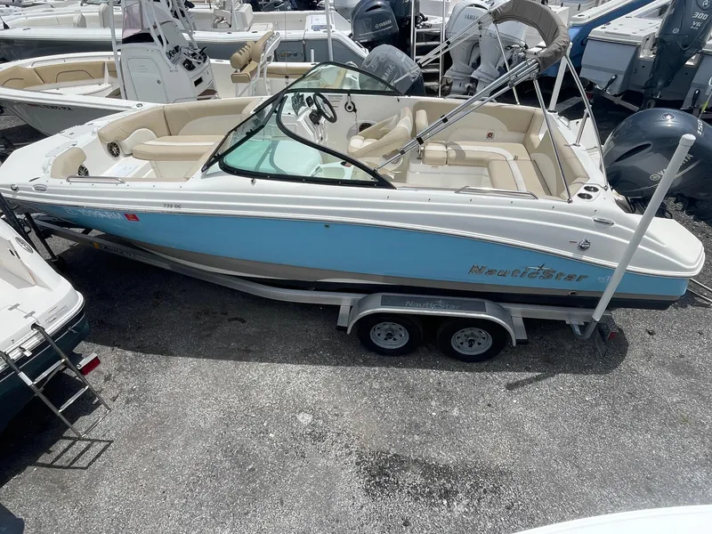 Slide: The Image of 2018 NauticStar 223DC Sport Deck boat on a trailer in a marina. - 3