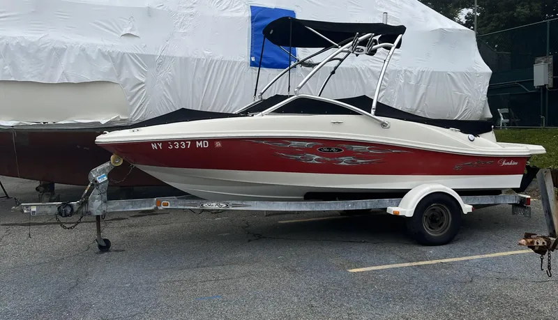 The Image of 2007 Sea Ray 185 Sport boat on trailer, red and white design, parked outdoors. - 0