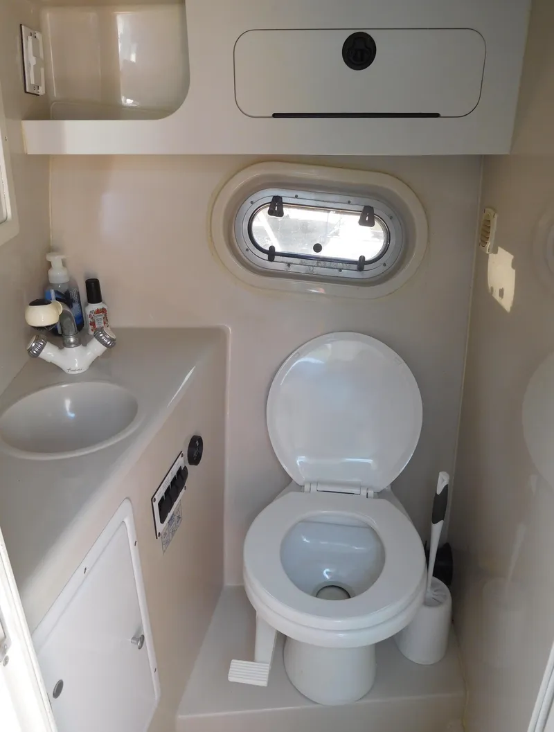 Slide: The Image of 2001 Four Winns 298 Vista boat bathroom with sink, toilet, and porthole window. - 29
