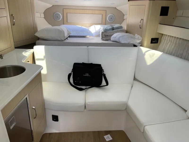 Slide: The Image of Interior of 2025 Regal 33 Express boat with white seating and compact kitchen area. - 8