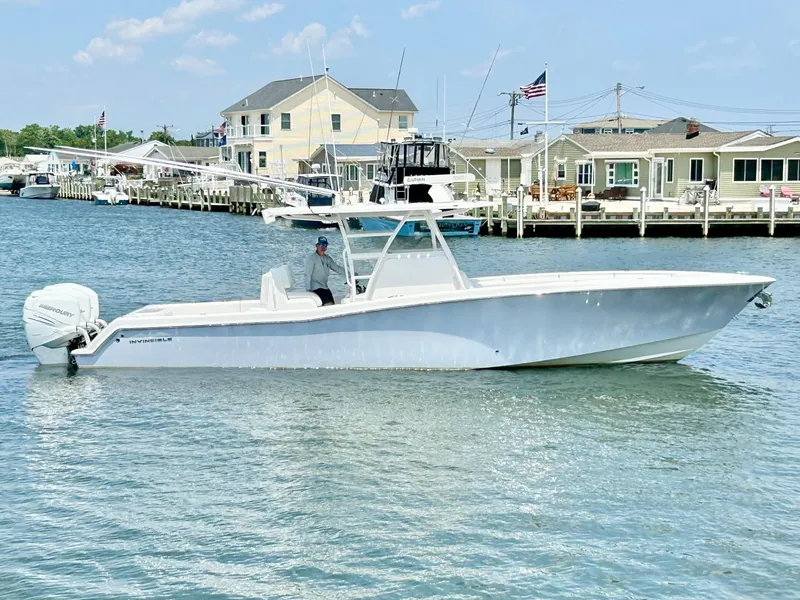 Slide: The Image of 2018 Invincible 36 Open boat cruising near a dockside community. - 4