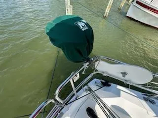 Slide: The Image of 1983 Catalina 30 Tall Rig sailboat with green cover, docked on calm water. - 23