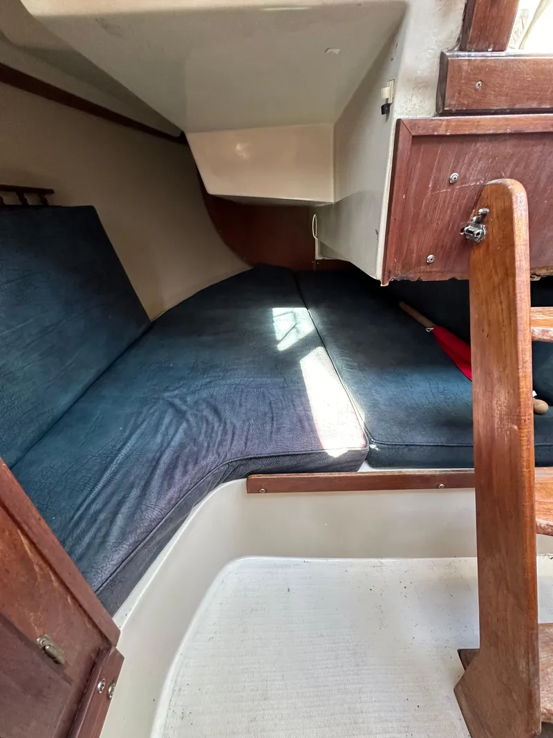 Slide: The Image of 1983 Catalina 30 Tall Rig interior cabin with blue cushions and wooden accents. - 49