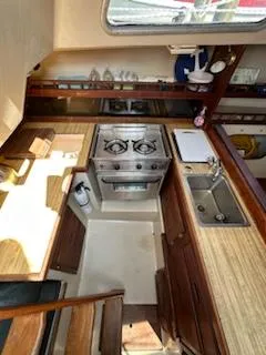 Slide: The Image of 1983 Catalina 30 Tall Rig yacht kitchen with stove, sink, and wooden cabinetry. - 6