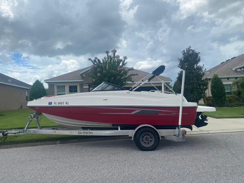 The Image of 2016 Bayliner 195 Deck Boat on a trailer in a residential neighborhood. - 0