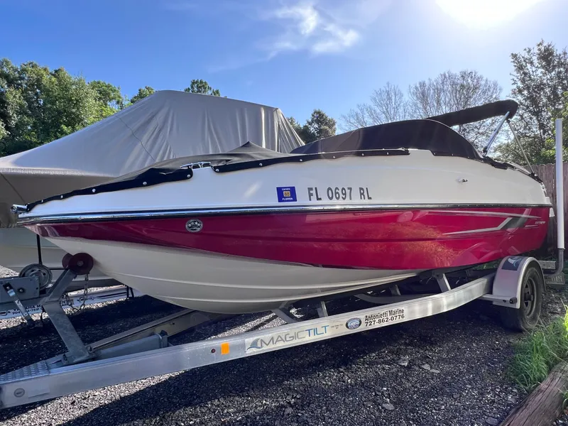 Slide: The Image of 2016 Bayliner 195 Deck Boat on a Magic Tilt trailer, red and white, parked outdoors. - 1