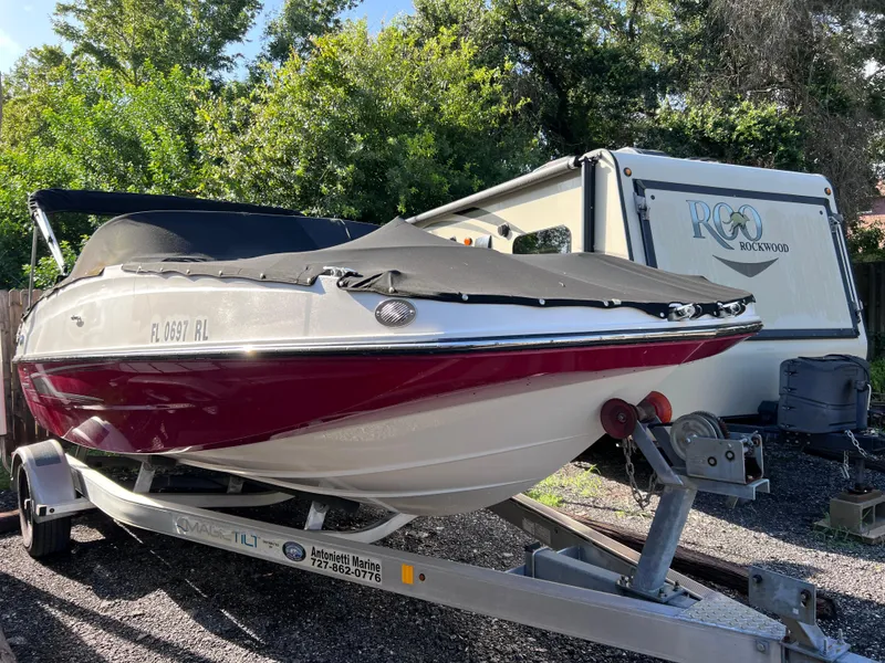 Slide: The Image of 2016 Bayliner 195 Deck Boat on trailer, parked outdoors near RV. - 2