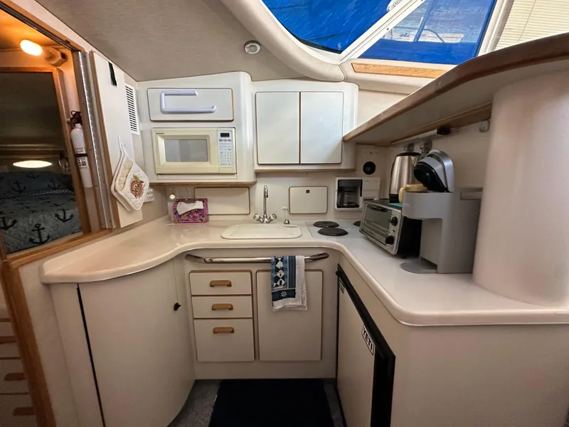 Slide: The Image of 1996 Sea Ray 370 Sedan Bridge kitchen with microwave, sink, and appliances. - 32