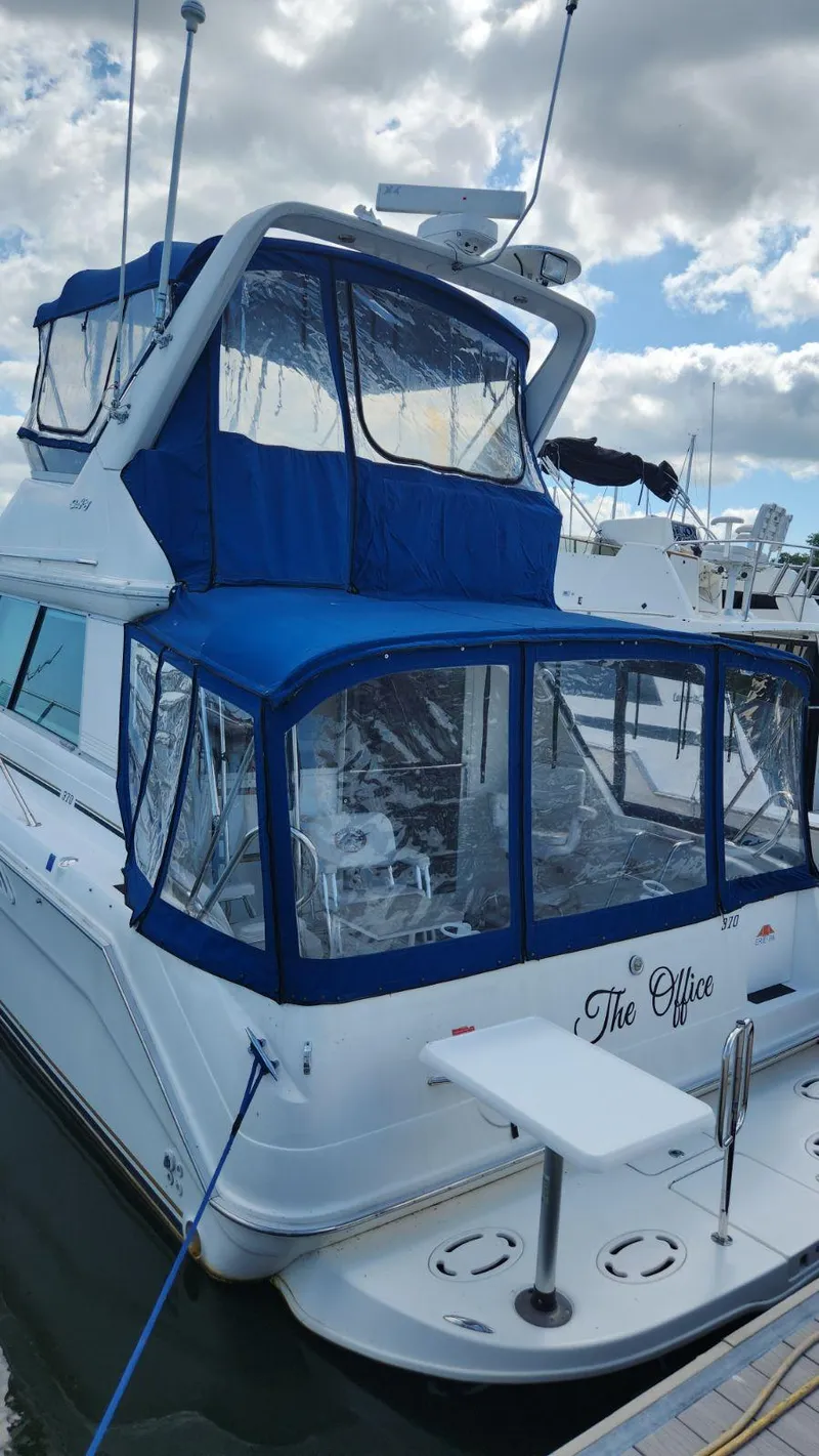 Slide: The Image of 1996 Sea Ray 370 Sedan Bridge docked, featuring blue canvas enclosures and upper helm station. - 4