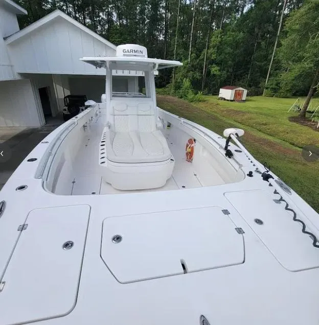 Slide: The Image of 2022 Invincible 33 Catamaran boat docked near a house with lush greenery. - 6