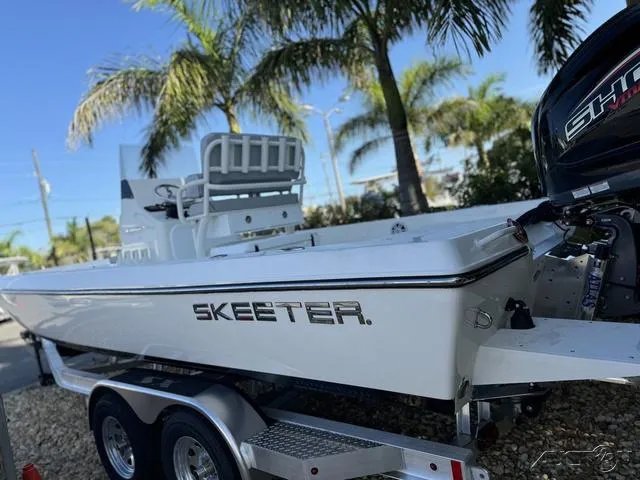 Slide: The Image of 2024 Skeeter SX230 boat on trailer with palm trees in background. - 17