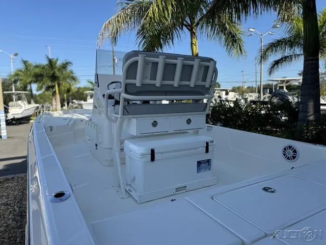 Slide: The Image of 2024 Skeeter SX230 boat interior with seating and storage, palm trees in the background. - 19