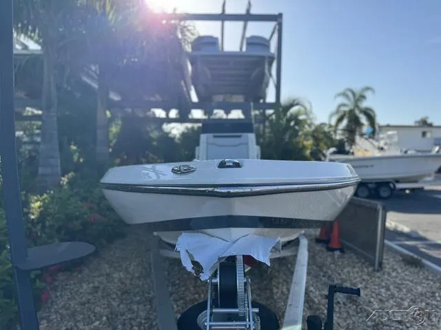 Slide: The Image of 2024 Skeeter SX230 boat on trailer, outdoor display with palm trees. - 5