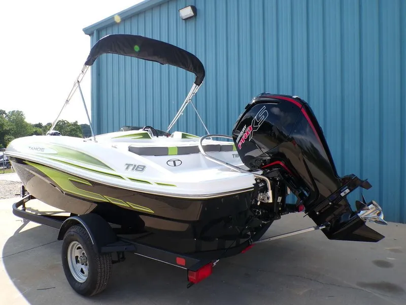 Slide: The Image of 2024 Tahoe T18 boat with outboard motor, parked on a trailer near a blue building. - 13