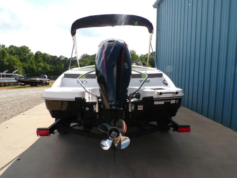 Slide: The Image of 2024 Tahoe T18 boat rear view with outboard motor, parked near blue building. - 3