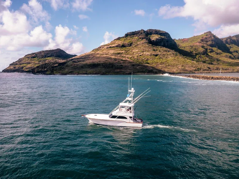 Slide: The Image of 1997 Buddy Davis Sportfisher Convertible cruising near scenic coastal cliffs. - 10