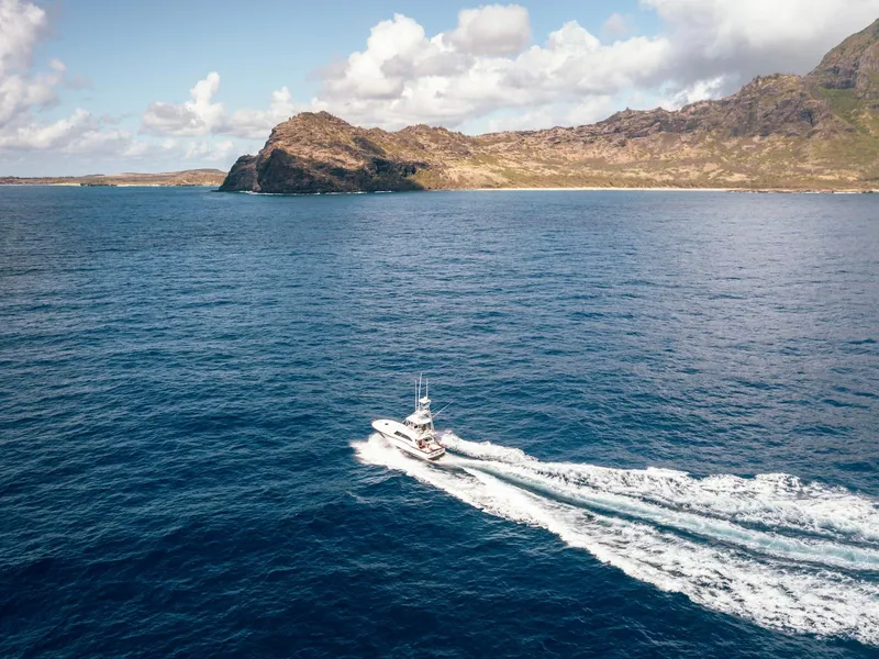 Slide: The Image of Aerial view of 1997 Buddy Davis Sportfisher Convertible cruising near a rocky coastline. - 17