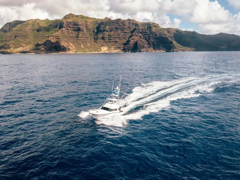 Slide: The Image of 1997 Buddy Davis Sportfisher Convertible cruising near scenic coastal cliffs. - 18