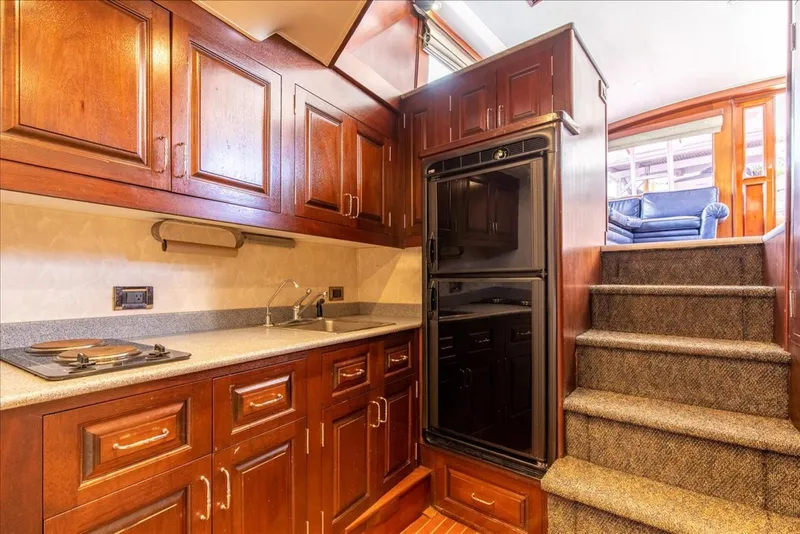 Slide: The Image of 1997 Buddy Davis Sportfisher Convertible kitchen with wooden cabinets and stairs. - 24