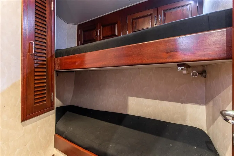 Slide: The Image of 1997 Buddy Davis Sportfisher Convertible interior with wooden bunk beds and storage cabinets. - 25