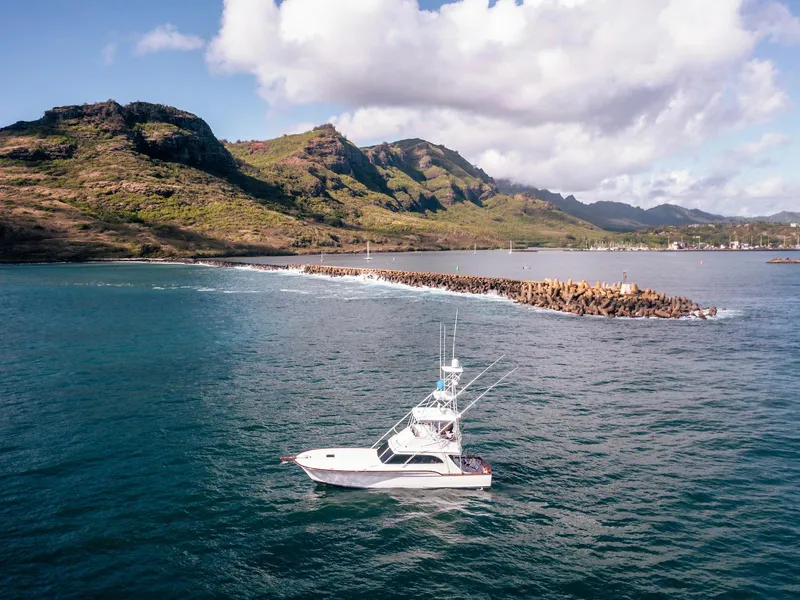Slide: The Image of 1997 Buddy Davis Sportfisher Convertible cruising near scenic coastal mountains. - 6