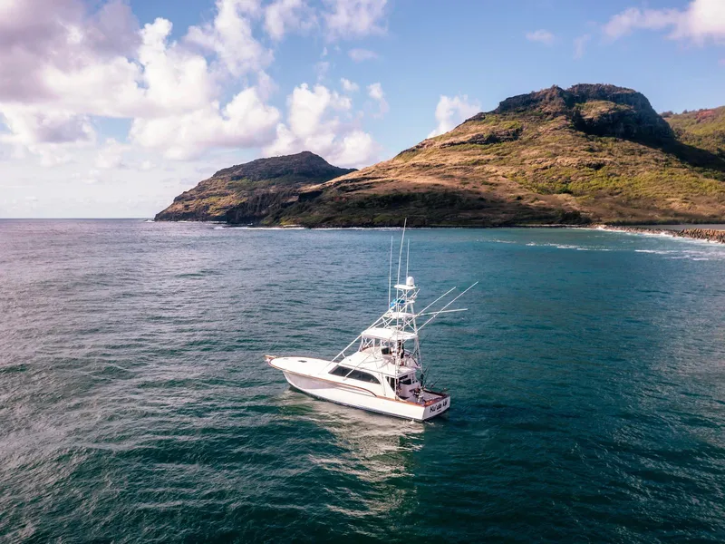 Slide: The Image of 1997 Buddy Davis Sportfisher Convertible cruising near scenic coastal cliffs. - 9