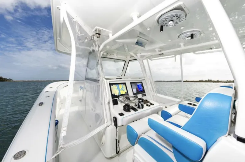 Slide: The Image of 2018 Yellowfin 39 boat interior with blue and white seating, navigation screens, and ocean view. - 14