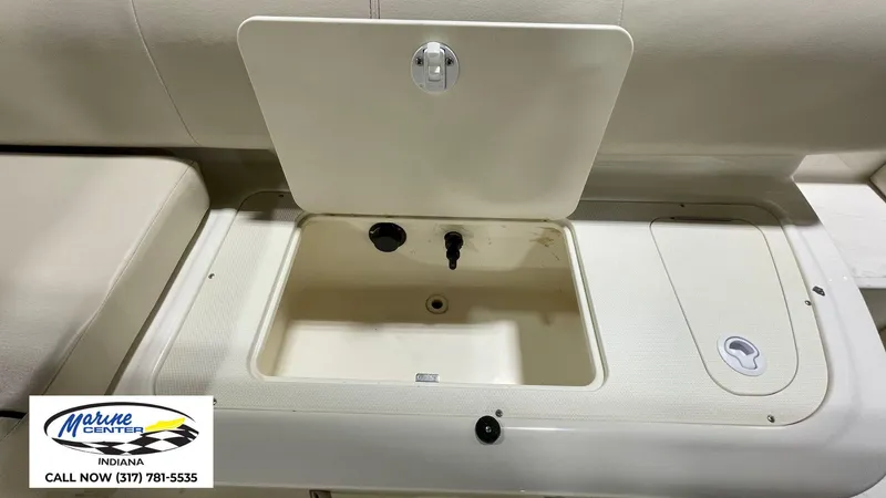 Slide: The Image of 2019 Bayliner 190 Deck Boat storage compartment with open lid, Marine Center contact info visible. - 3