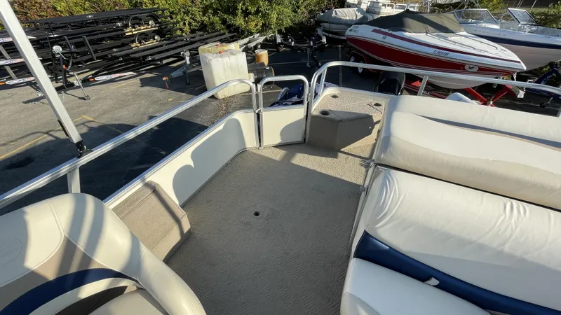 Slide: The Image of 2007 Sun Tracker Fishing Deck 21 interior with seating and railing, parked near other boats. - 17