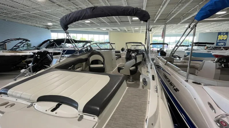Slide: The Image of 2017 Stingray 215LR boat interior in showroom, featuring seating and steering area. - 2