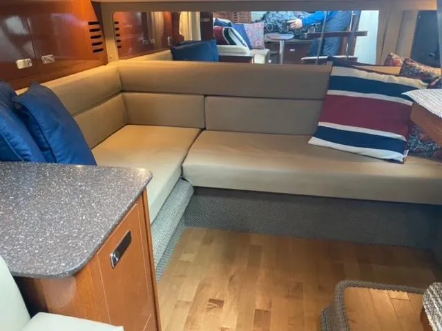 Slide: The Image of Interior of 2012 Sea Ray 370 Sundancer with beige seating and colorful pillows. - 13