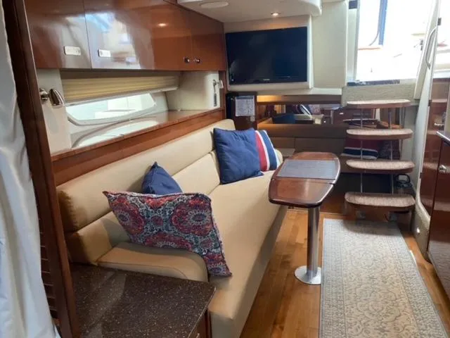 Slide: The Image of Interior of 2012 Sea Ray 370 Sundancer with beige sofa, colorful pillows, and wooden table. - 14