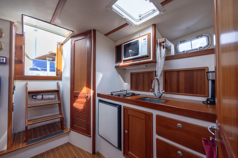 Slide: The Image of 1998 Little Harbor WhisperJet 36 yacht interior kitchen with wooden cabinets, microwave, and sink. - 24