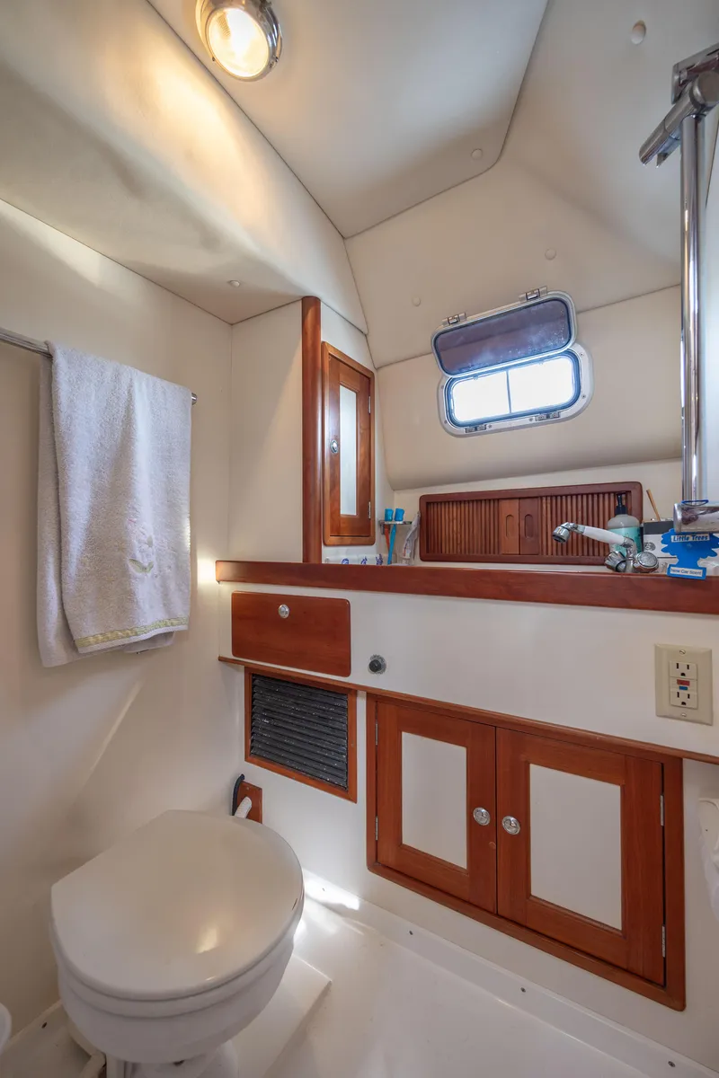Slide: The Image of 1998 Little Harbor WhisperJet 36 boat bathroom with wooden cabinets and porthole window. - 33