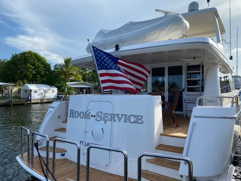 Slide: The Image of Luxury yacht "Room Service" docked, displaying American flag, West Bay 68 model, 2003. - 4