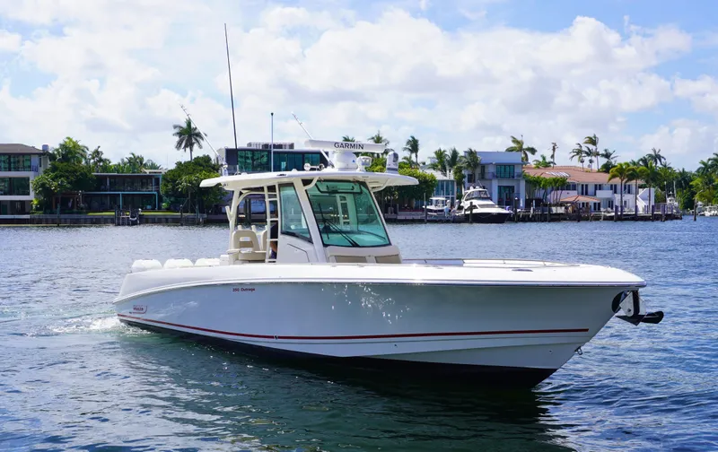 Slide: The Image of 2020 Boston Whaler 350 Outrage boat cruising on a sunny day near waterfront homes. - 3