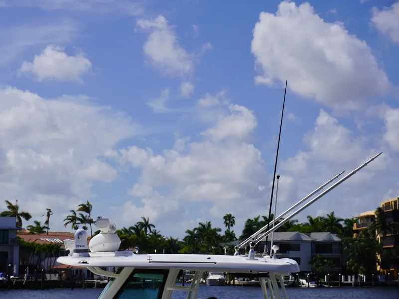Slide: The Image of Boston Whaler 350 Outrage 2020 boat with antennas against a blue sky and waterfront homes. - 5
