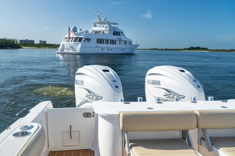 Slide: The Image of 2019 Everglades 355 Center Console with Yamaha engines, cruising near a luxury yacht. - 11