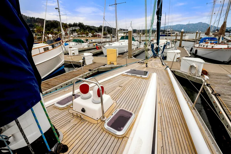 Slide: The Image of Nautor Swan 48 sailboat docked at marina, 2001 model, wooden deck, scenic background. - 16
