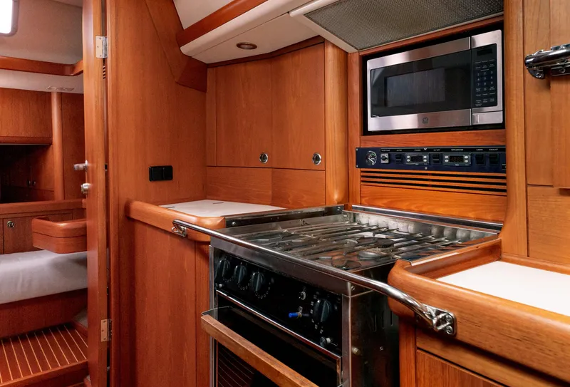 Slide: The Image of Nautor Swan 48 yacht kitchen interior, 2001 model, featuring stove, microwave, and wooden cabinetry. - 38