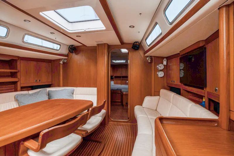 Slide: The Image of Luxurious interior of 2001 Nautor Swan 48 yacht with wooden furnishings and white seating. - 48