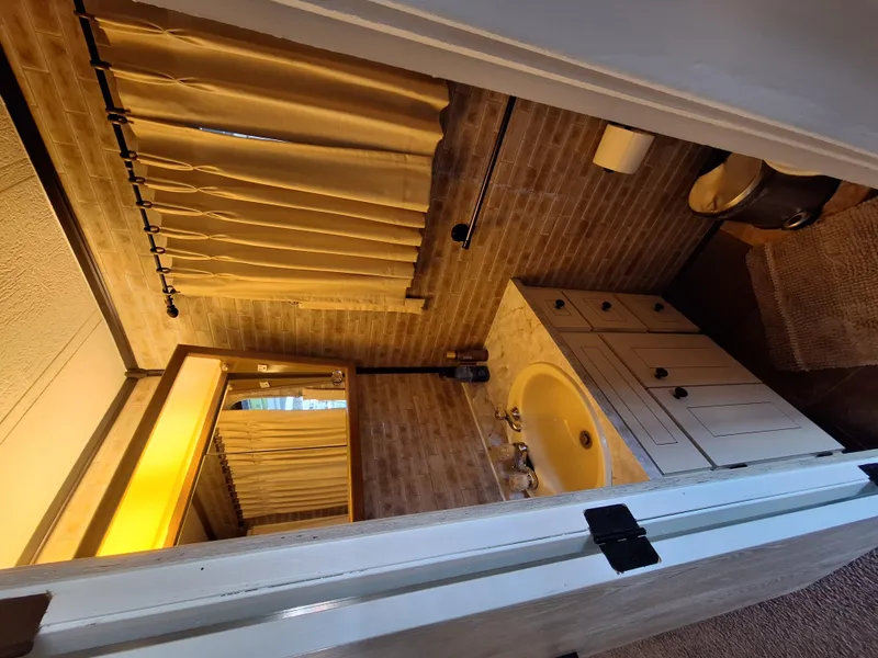 Slide: The Image of 1986 Skipperliner houseboat bathroom with sink, mirror, and beige curtains. - 11