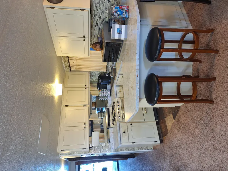 Slide: The Image of Interior of a 1986 Skipperliner houseboat kitchen with white cabinets and bar stools. - 18