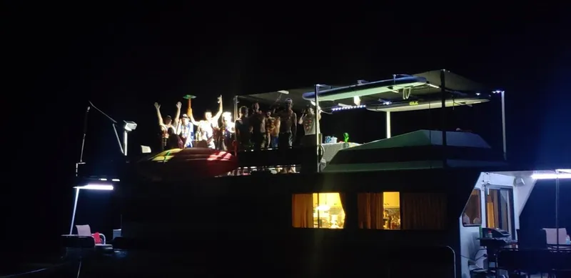 Slide: The Image of 1986 Skipperliner houseboat at night with a group of people partying on the deck. - 23