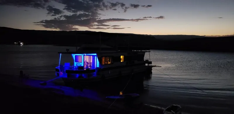 Slide: The Image of 1986 Skipperliner houseboat illuminated at dusk on a serene lake. - 24
