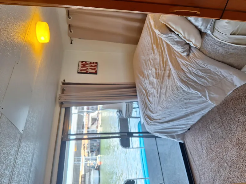 Slide: The Image of Interior of 1986 Skipperliner houseboat bedroom with bed, window, and lake view. - 9